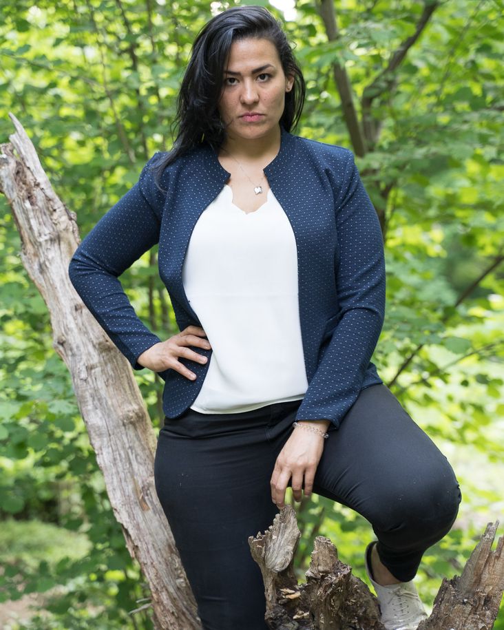 mujer de aspecto serio vestida con una blazer en el bosque