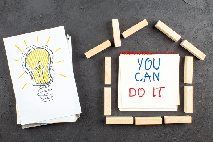 Drawing of light bulb and wooden blocks in the shape of a paper house with a note “you can do it”