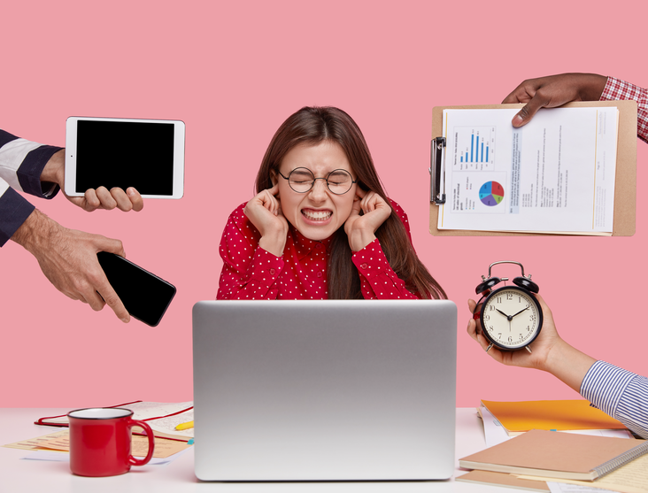 Brunette woman, sitting at desk, surrounded by distractions at work