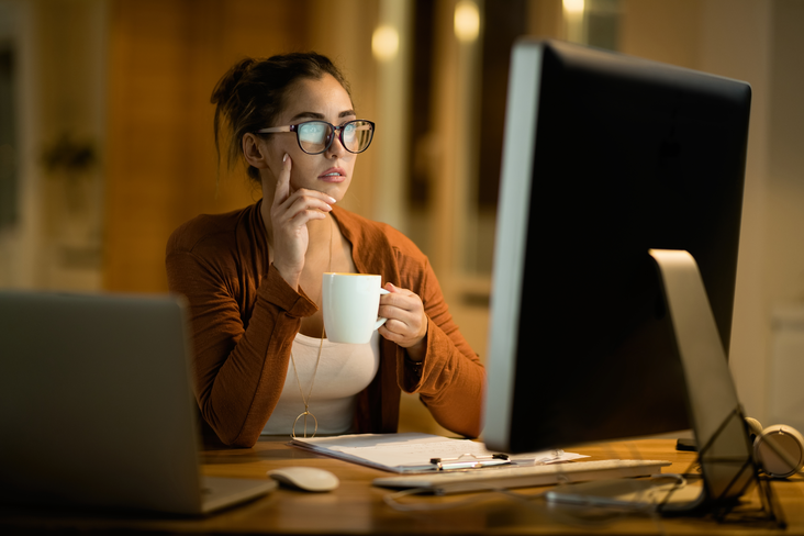 Woman drinking coffee and working on desktop