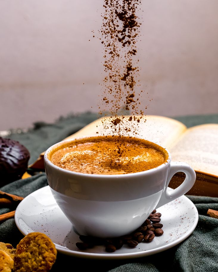 Eine Tasse Cappuccino, umgeben von Keksen und einem Buch