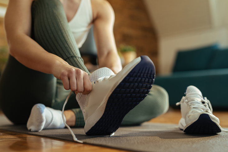 Frau, die sich Turnschuhe anzieht