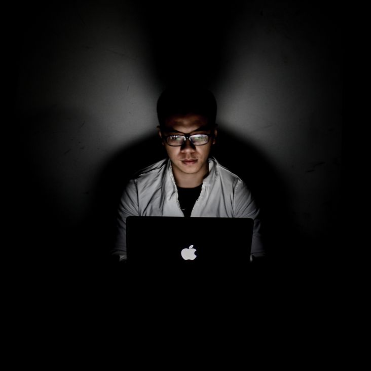 Mann arbeitet im Dunkeln am Computer