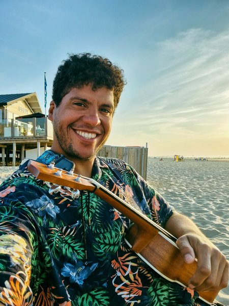 Dr. Urbina-Blanco am Strand mit einer Ukulele