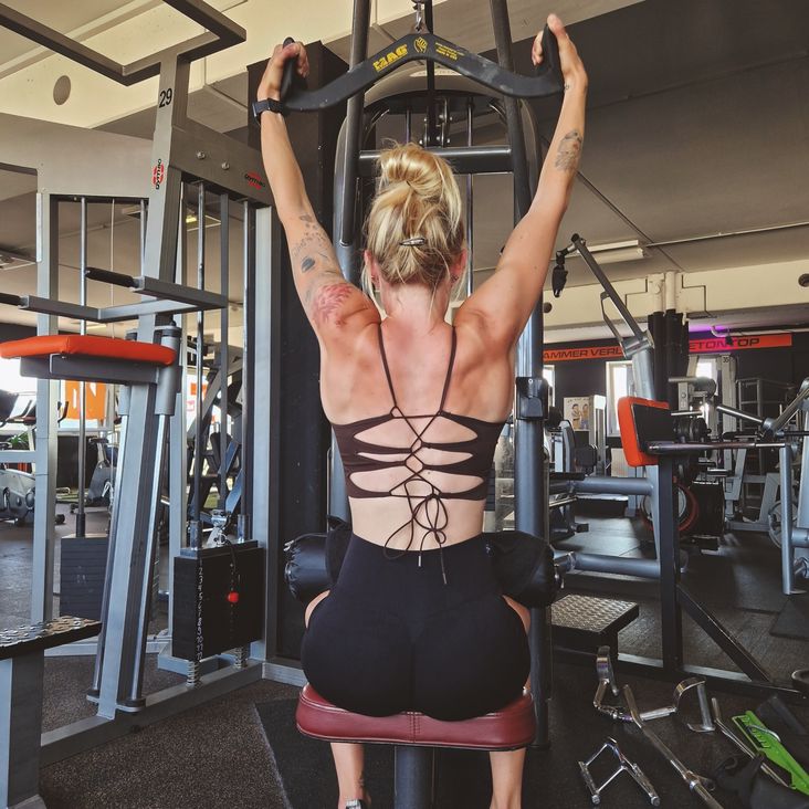 Foto einer Blondine beim Training im Fitnessstudio, Pull-up