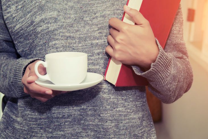 Frau mit einer Tasse und einem Buch