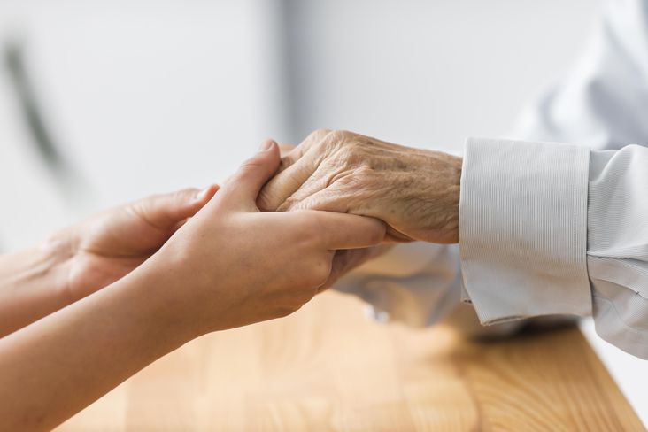 Krankenschwester hält die Hand eines älteren Menschen