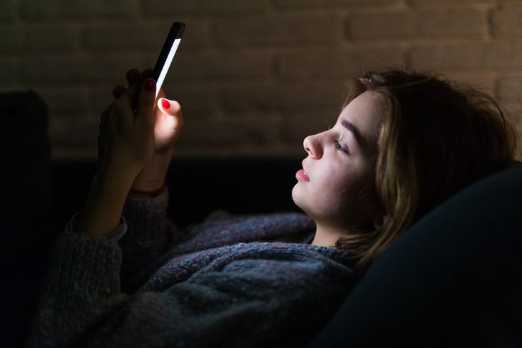 Frau, die nachts im Bett ihr Smartphone benutzt