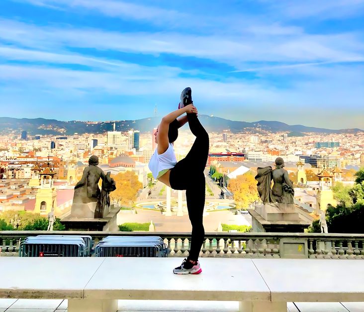 Pose gimnasia. Gimnasta femenina de pie sobre una pierna, sujetando el otro pie por detrás de la nuca en Barcelona 